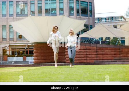 Zwei Frauen laufen fröhlich auf dem Gras in der Stadt Stockfoto
