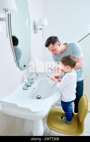 Vater und Sohn putzten im Badezimmer die Zähne zusammen. Stockfoto