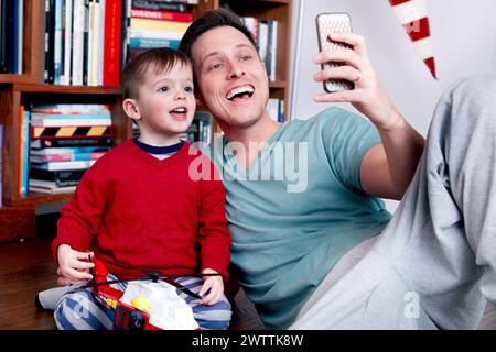 Mann und Kind machen ein Selfie auf der Couch Stockfoto