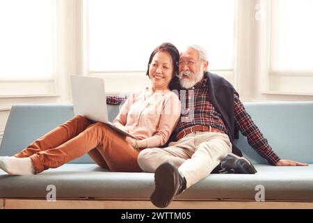 Älteres Ehepaar, das sich auf einem Sofa mit Laptop entspannt Stockfoto