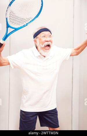 Senior-Mann posiert mit einem Tennisschläger Stockfoto