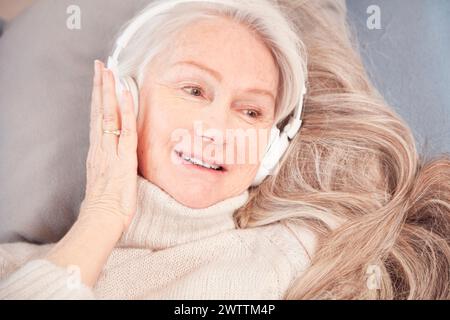 Eine ältere Frau lächelt mit Kopfhörern Stockfoto