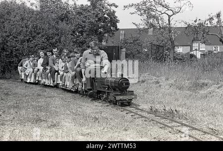 1960er Jahre, historisch, Sommer und draußen bei einer Miniaturbahn, Familien mit einer kleinen Dampfeisenbahn, England, Großbritannien. Stockfoto