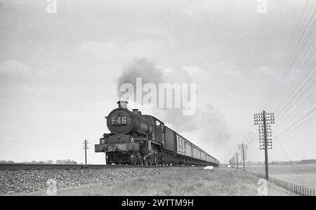 Ende der 1950er Jahre, historische Vorderansicht einer Great Western Railway (GWR) King Class Dampflokomotive F46 mit Wagen auf der Schiene, England, Großbritannien. Stockfoto