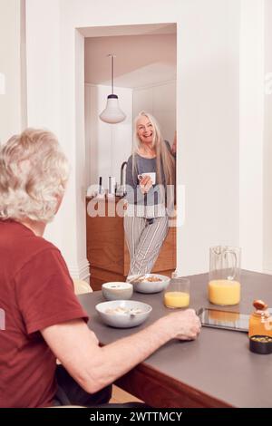 Eine ältere Frau lächelt in der Tür auf sitzenden Mann Stockfoto