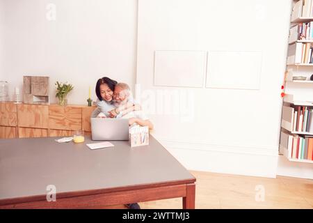 Ein lächelndes Paar, das zu Hause an einem Laptop teilnimmt Stockfoto