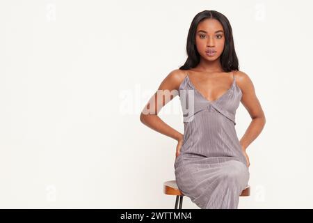Frau posiert in einem grauen Kleid auf weißem Hintergrund Stockfoto