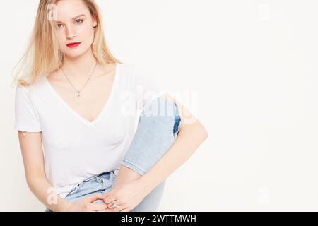 Frau posiert in einem weißen T-Shirt und einer blauen Jeans Stockfoto