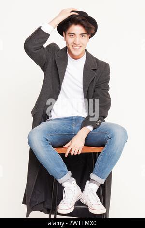 Stilvoller Mann, der mit einem Hut sitzt und lächelt Stockfoto