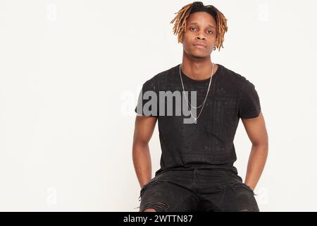 Junger Mann mit Dreadlocks, der in schwarzer Kleidung posiert Stockfoto
