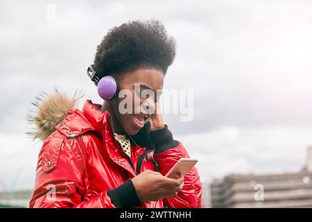 Frau mit Kopfhörern über Smartphone Stockfoto