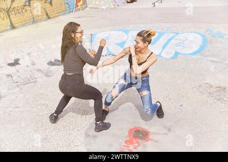 Zwei Frauen tanzen auf einer mit Graffiti bedeckten Straße Stockfoto