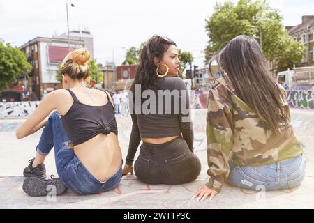 Drei Frauen sitzen draußen bei einem Skatepark Stockfoto