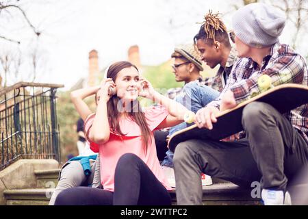 Gruppe junger Freunde, die mit einem Skateboard auf Stufen sitzen Stockfoto
