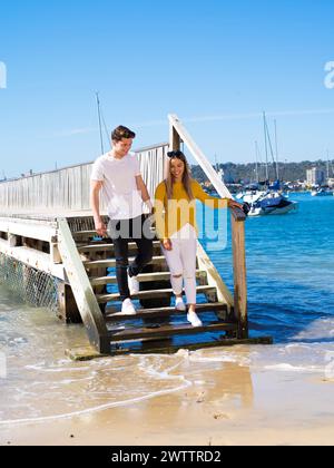 Ein Paar, das einen hölzernen Pier am Meer hinuntergeht Stockfoto