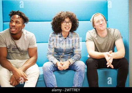 Drei Leute sitzen zusammen auf einer blauen Couch Stockfoto