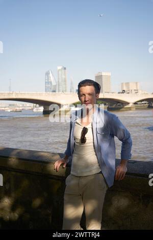Person posiert vor einem Fluss mit einer Skyline der Stadt Stockfoto