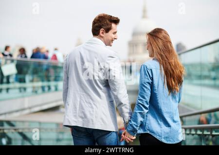 Ein paar, das Hände an einer Stadtbrücke hält Stockfoto