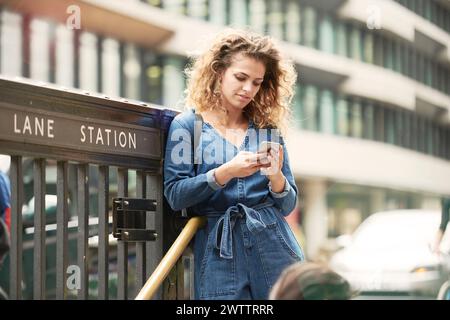 Frau, die ein Smartphone am Bahnhof benutzt Stockfoto