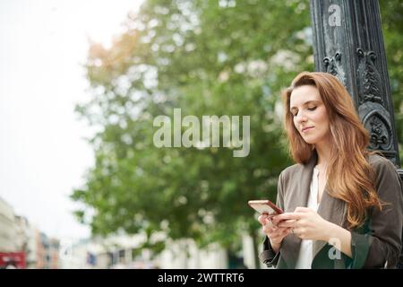 Frau, die auf der Straße in der Stadt ein Smartphone benutzt Stockfoto