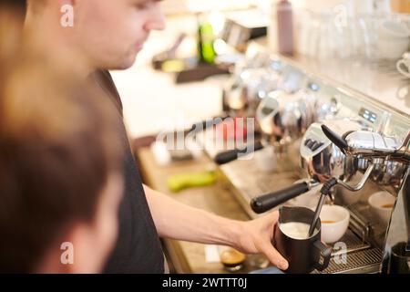Der Barista schäumt Milch an einer Kaffeemaschine auf Stockfoto