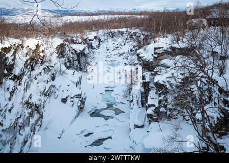 Arktische Landschaft mit Schnee, Eis, Wasser und steilen Felswänden in der Abisko River Gorge im Abisko National Park, Schweden. Stockfoto