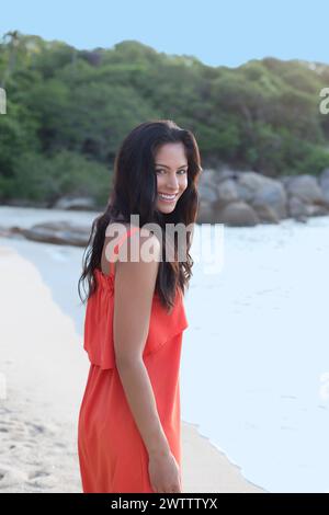 Frau in orangefarbenem Kleid am Strand Stockfoto