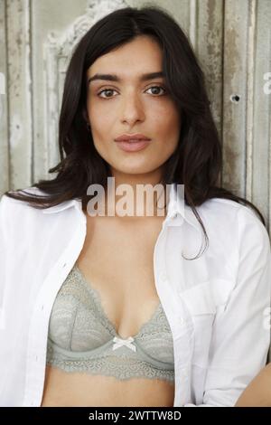 Frau posiert in einem weißen Hemd und grauem BH Stockfoto