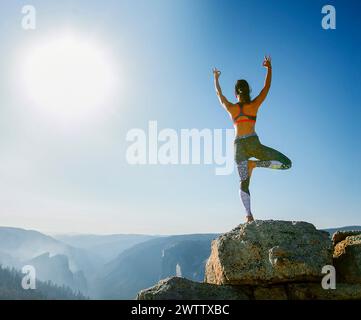 Frau, die Yoga auf einem Berggipfel bei Sonnenaufgang macht Stockfoto