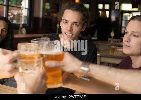 Freunde, die in einem Pub mit Biergläsern tosten Stockfoto