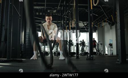 Kaukasischer Fitness-Mann, der mit Kampfseil-Cross-Training im Fitnessstudio trainiert starker muskulöser Sportler männlicher Bodybuilder Athlet aktive Cardio-Übung Stockfoto