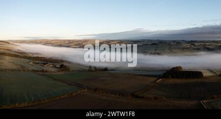 Aus der Vogelperspektive auf niedrig liegende Nebel- oder Wolkenumkehr entlang des River Tyne Valley an der Haydon Bridge nahe Hexham an einem kalten Wintermorgen Stockfoto