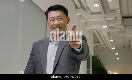 Zufriedener asiatischer Mann glücklicher Geschäftsmann mittleren Alters koreanischer chinesischer, japanischer, ethnischer Arbeitgeber, Unternehmer, Geschäftsführer, der mit Daumen nach oben zeigt Stockfoto