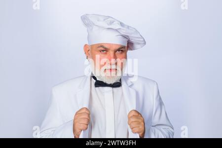 Portrait ernster, gutaussehender bärtiger Mann in Uniform und Kochmütze. Professioneller Koch oder Bäcker in Kochmütze. Kochen und kulinarisches Konzept. Selbstbewusster männlicher Mann Stockfoto