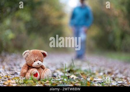 Ein Mann im besten Alter, der im Herbst draußen einen Teddybären in einem Wald tritt Stockfoto