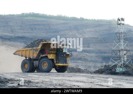 Großer gelber Lkw, der Kohle aus dem Steinbruch transportiert. Kohlebergbau Stockfoto