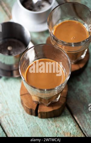Vietnamesischer Kaffee in Glasbechern auf alten Brettern, offener phin-Filter von oben Stockfoto