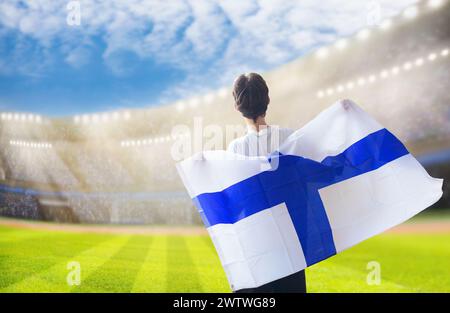 Finnischer Fußballfan im Stadion. Finnische Fans auf dem Fußballfeld beobachten das Spiel der Mannschaft. Gruppe von Fans mit Flagge und Nationaltrikot Stockfoto