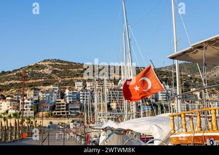 Rote türkische Flagge flattert mit Segelbooten im Hintergrund an einem Yachthafen. Stockfoto