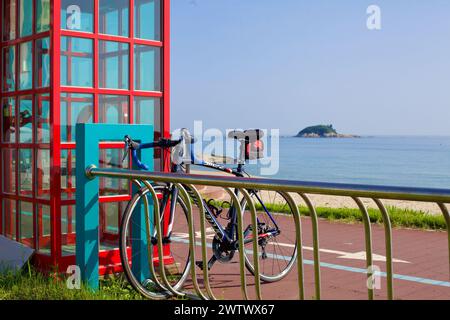 Goseong County, Südkorea - 30. Juli 2019: Ein Fahrrad, das sicher auf einem Rack neben dem Bongpo Beach Certification Center geparkt wird, mit der ruhigen Jukdo Isla Stockfoto
