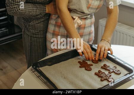 Zwei Personen sind aktiv an der Herstellung von Cookies in einer Küche beteiligt. Sie mischen Zutaten, Formen Teig und legen Co Stockfoto