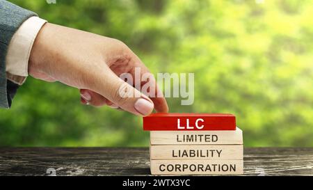 Business Hand legte einen Stapel Holzblöcke mit dem Text LLC, der Abkürzung für Limited Liability Company, ein. Geschäftskonzept Stockfoto