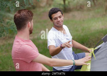 Junge Männer, die ein Zelt auf dem Land aufbauen Stockfoto