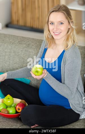 Glückliche schwangere Frau, die einen Apfel hält Stockfoto