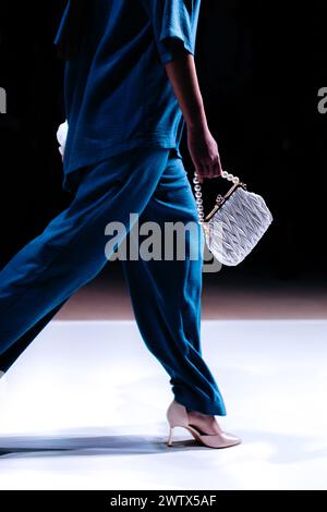 Kleine weiße Handtasche Clutch in der Hand der Frau, blaue Bluse und Hose. Stylische, moderne Damenmode Stockfoto
