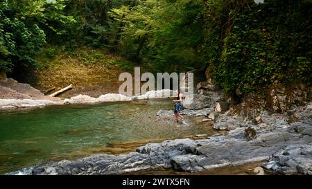 Wanderer, die an einem schönen Sommertag im Fluss läuft. Kreativ. Paradies Wasserreservoir im Dschungel. Stockfoto