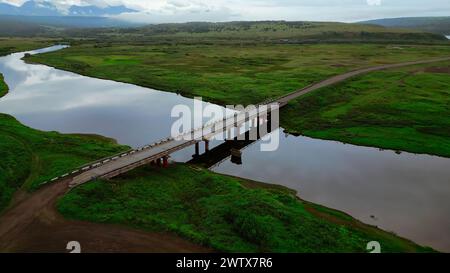 Sommerblick auf den schmalen Fluss, der ins Meer fließt. Clip. Betonbrücke, die den ruhigen Fluss überquert. Stockfoto