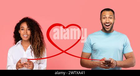 Eine Frau mit lockigen Haaren und einem weißen Hemd schaut ihr Handy mit einem Lächeln an, während ein Mann in einem blauen T-Stück ihm angrinst Stockfoto