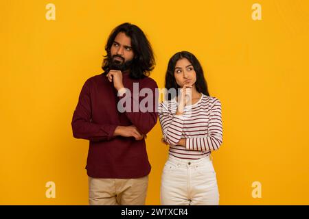 Nachdenkliches Paar mit nachdenklichen Ausdrücken auf Gelb Stockfoto