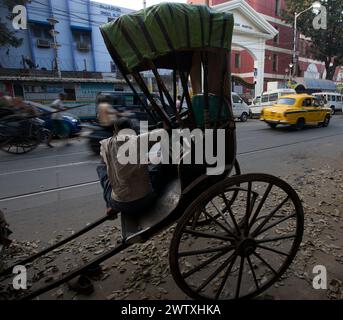 Ein Sat-Rikscha-Fahrer wartet auf Kunden auf einer Straße in Kalkutta, Westbengalen, Indien Stockfoto